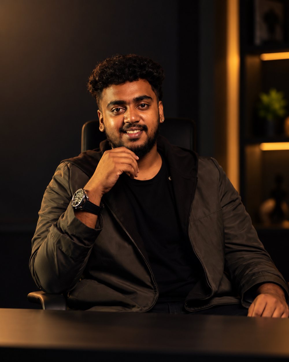 Gokul Krishna, founder and creative director of The Heist Frame, seated at a desk in a black jacket